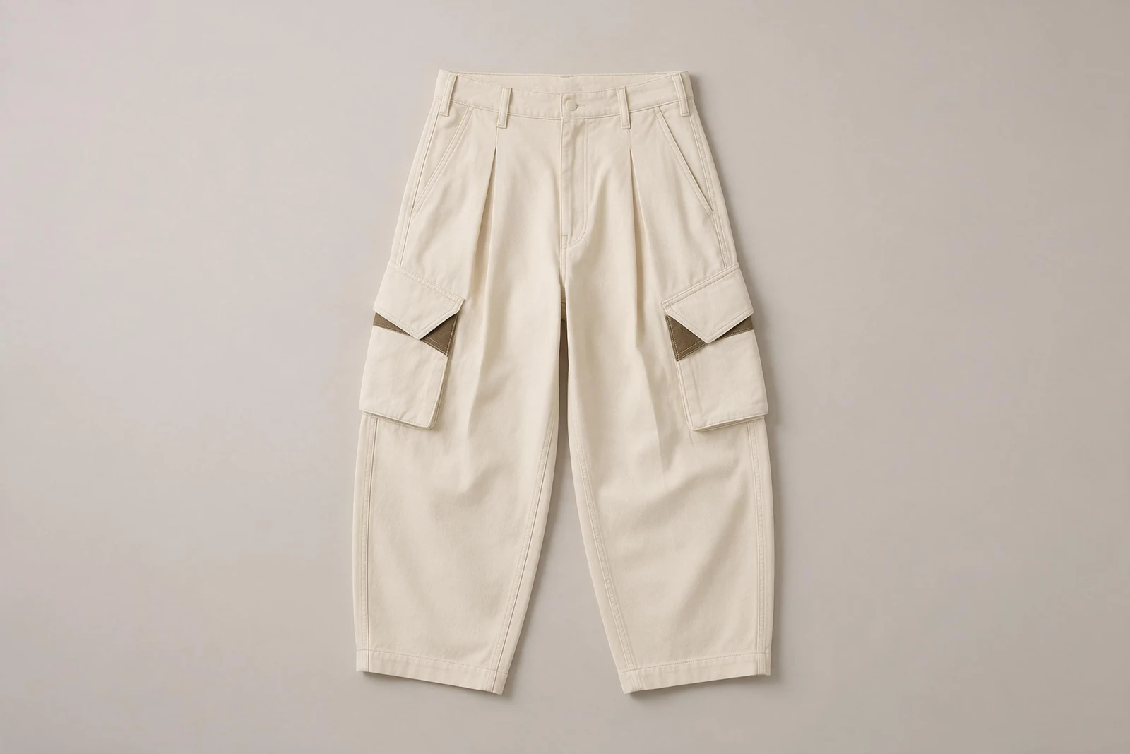 Bone-white curved-leg cargo pants laid flat with angled pocket flaps and dark brown inserts.