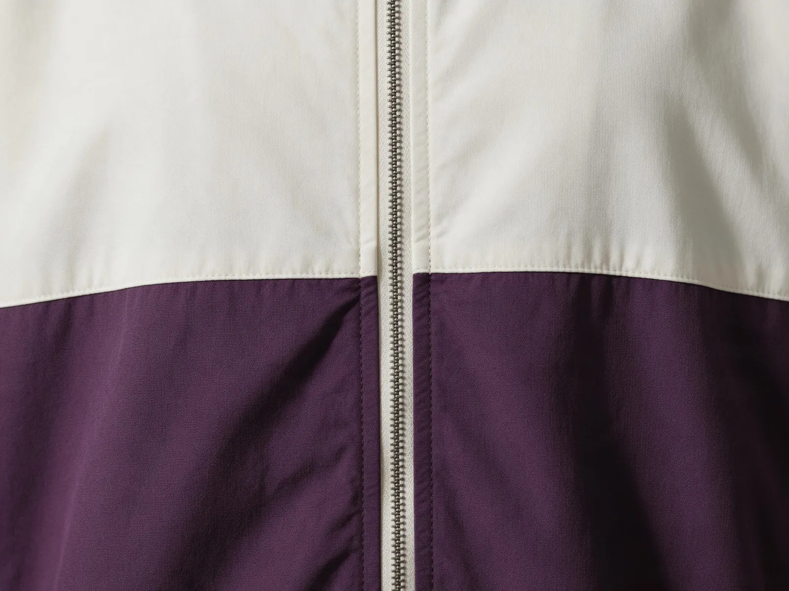 Close-up of cream and aubergine fabric panels meeting on either side of a central zip.