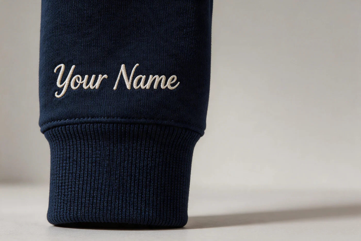 Navy hoodie sleeve with Your Name lettering above the ribbed cuff.