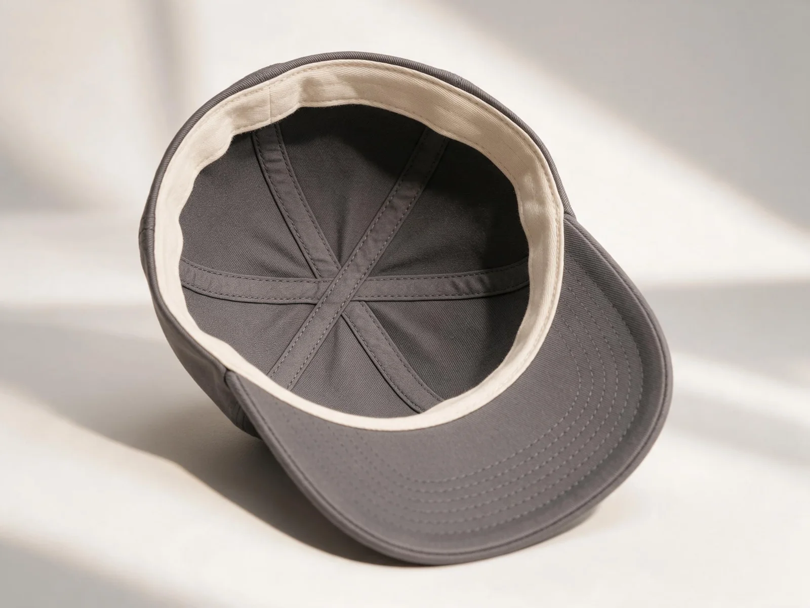 Interior of a charcoal cap with a pale inner band and covered panel seams.