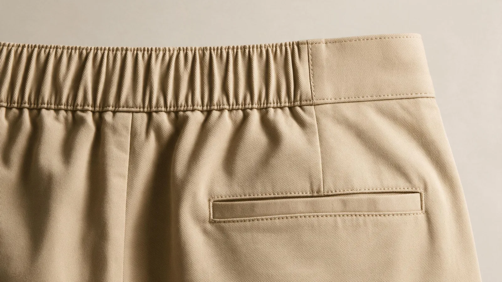 Sand-coloured waistband detail showing a gathered section beside a smooth section.