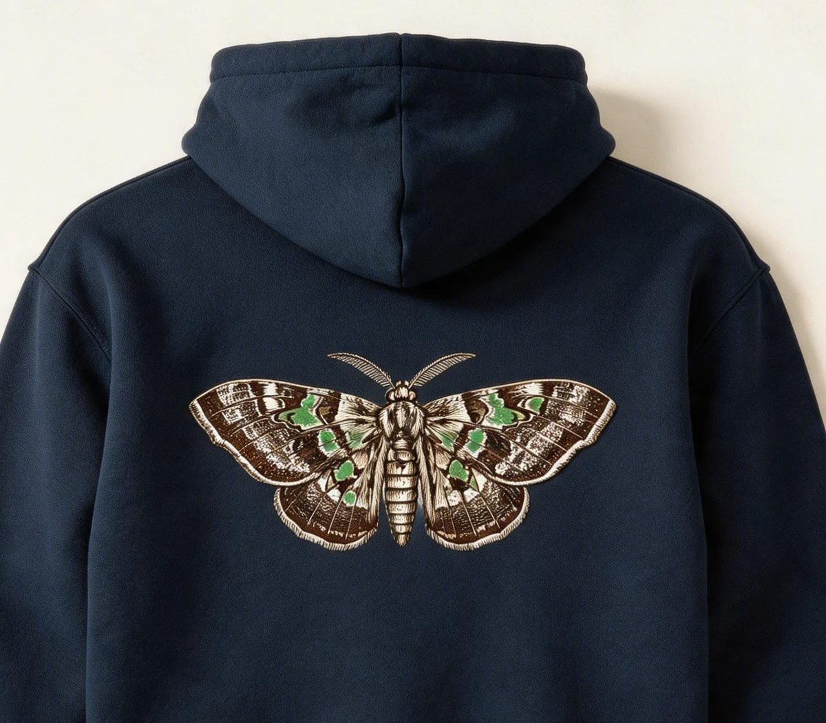 Detail of dark hoodie with a spread-wing moth motif on the back.