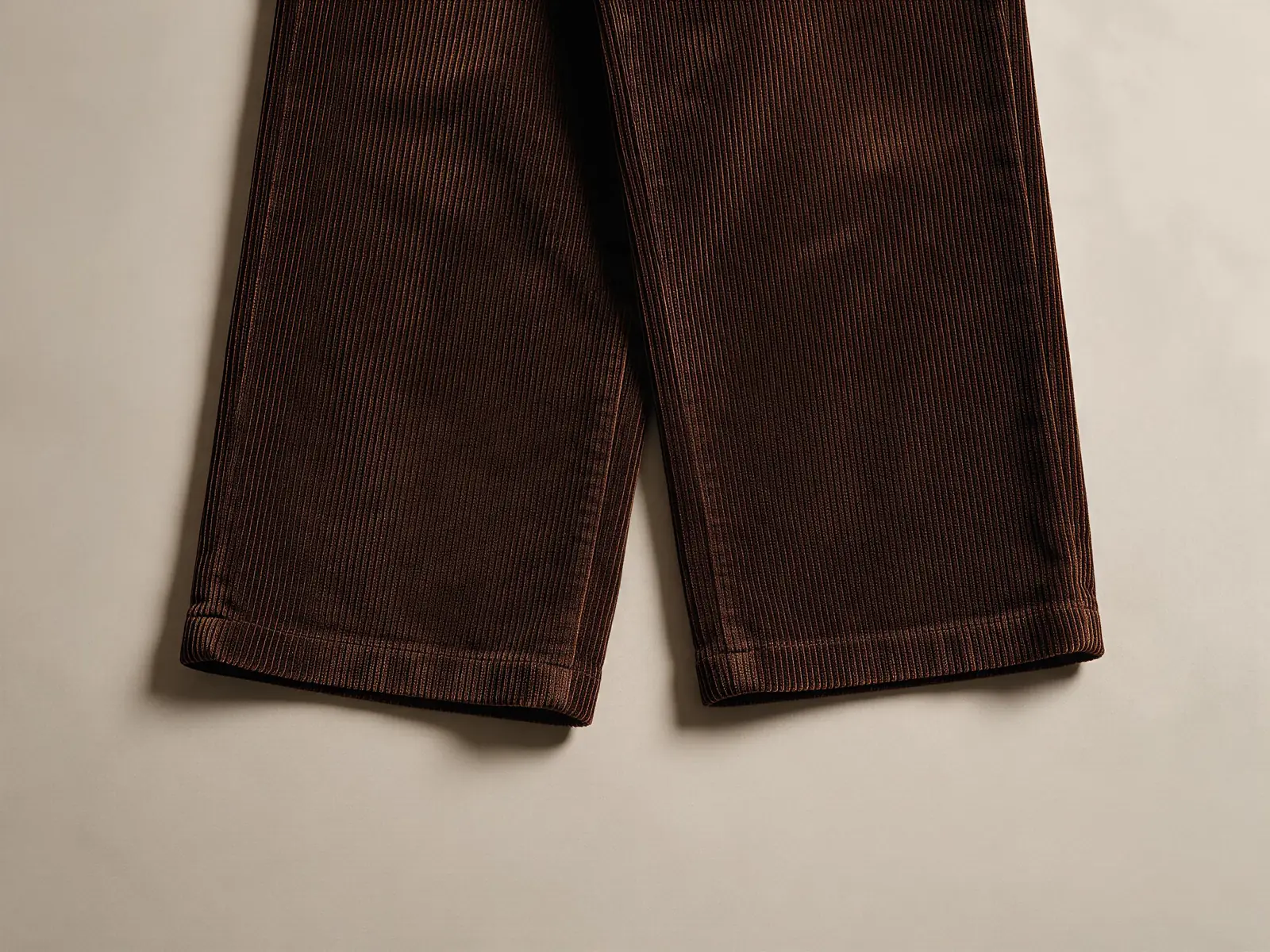 AI design concept dark brown corduroy trousers, close view of two straight hems with visible stitching lines